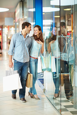 Buy stock photo Happy, couple and talk in mall with shopping bag, planning purchase and bonding together on weekend. People, dating and customer discussion at store with retail sale, cashback promotion and discount.