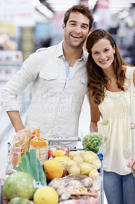Buy stock photo Smile, portrait and couple with cart in grocery store, supermarket and shopping deals on weekend. Happy, relationship and man with woman with embrace, food and produce for discount, sale and bonding