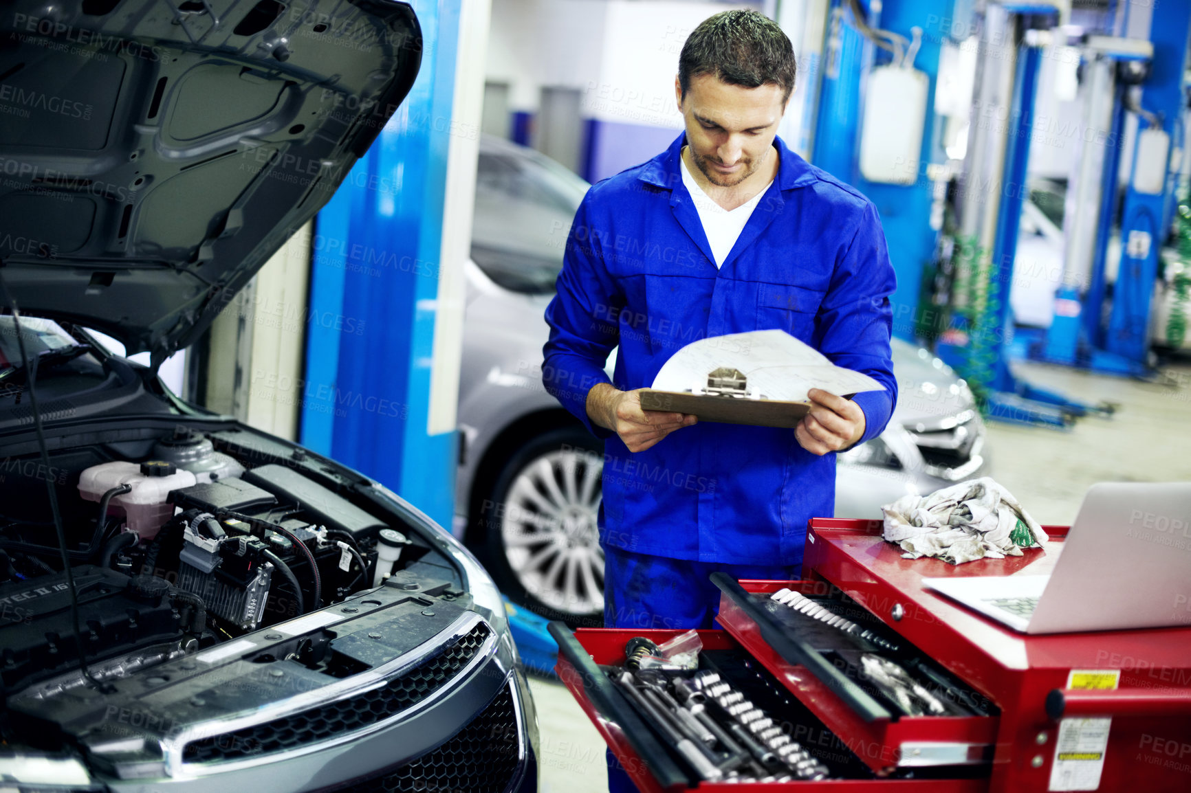 Buy stock photo Man, inspection and car mechanic in workshop with clipboard, engine assessment and maintenance service. Technician, person and reading in garage with checklist, vehicle evaluation or review paperwork