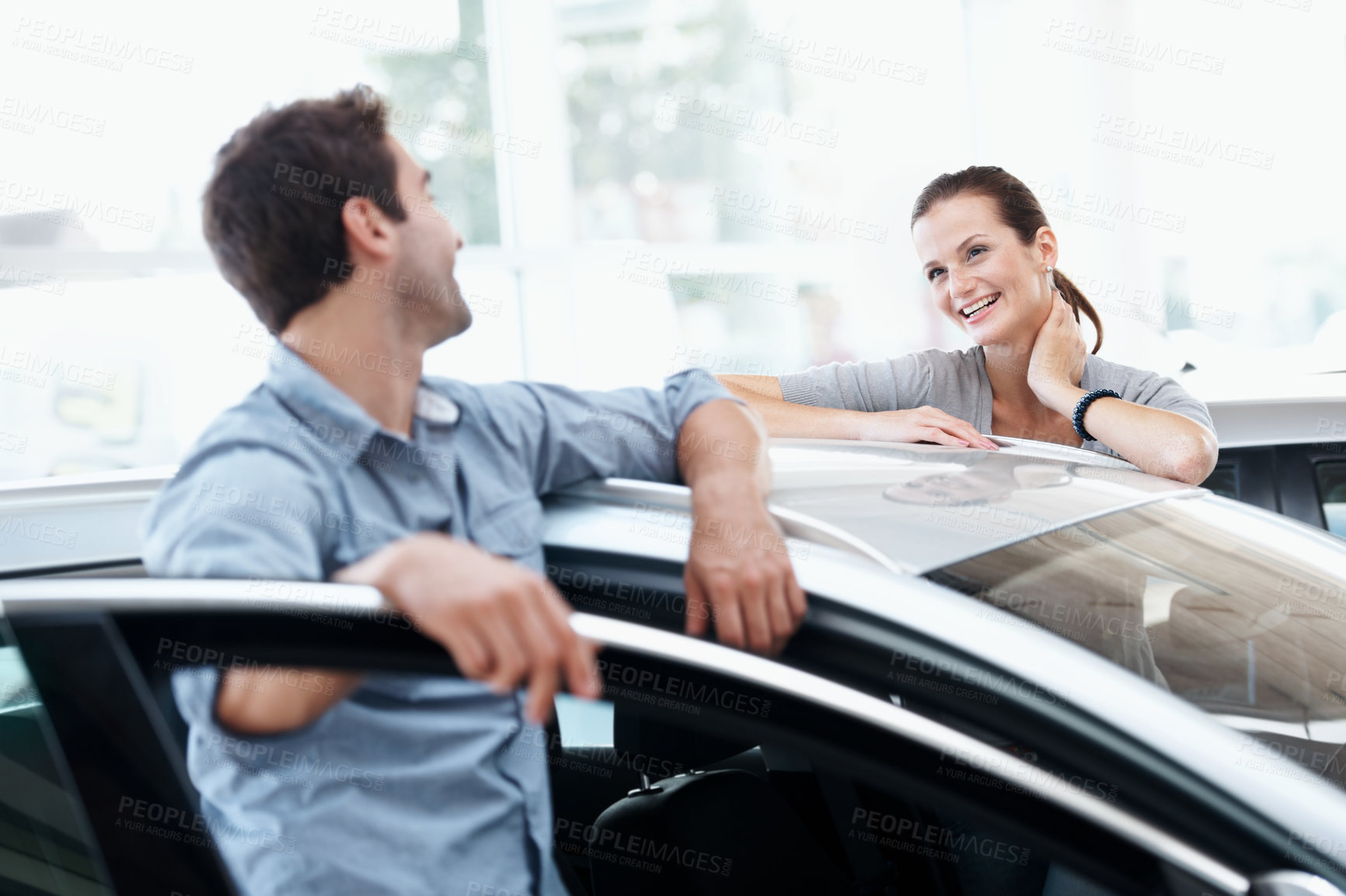 Buy stock photo Couple, talking and happy at car dealership with choice for purchase, buying and decision for vehicle. Man, woman and smile by door for rental option, insurance or showroom for customer or client