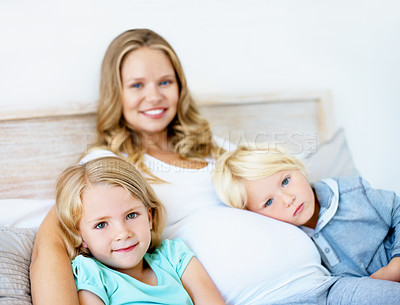 Buy stock photo Portrait of a pregnant mother with her little son and daughter sitting together at home