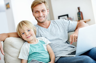Buy stock photo Handsome dad and his cute son smiling at the camera with their laptop at home