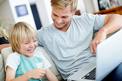 Buy stock photo Cute little boy laughing with his dad while using a laptop on the couch