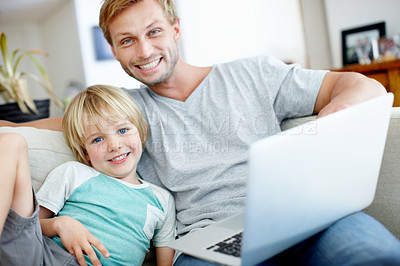 Buy stock photo Handsome dad and his cute son smiling at the camera with their laptop at home