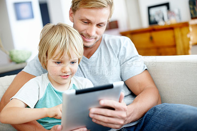 Buy stock photo Handsome dad teaching his cute little son to use their new digital tablet