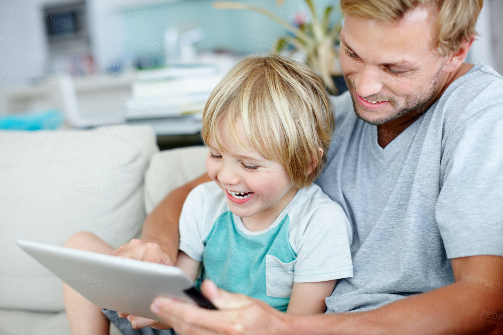 Buy stock photo Loving father and son laughing while playing a game on a digital tablet at home