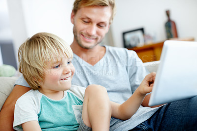 Buy stock photo Cute little boy learning how to use a digital tablet with his dad at home