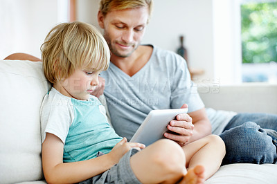 Buy stock photo Cute little boy learning how to use a digital tablet with his dad at home