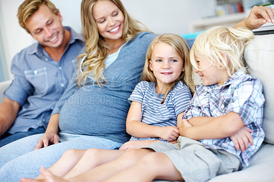 Buy stock photo Cute young family of four sitting together on the sofa at home