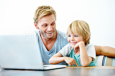 Buy stock photo A little boy sitting at his laptop while his father helps him 