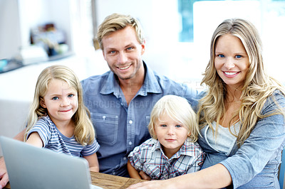 Buy stock photo Cute young family looking at a laptop together while at home