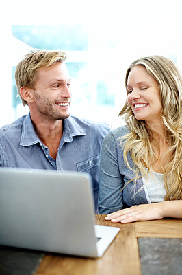 Buy stock photo Happy young couple looking at a laptop together at home