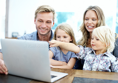Buy stock photo Cute young family looking at a laptop together while at home