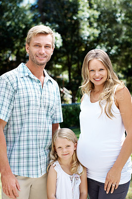 Buy stock photo Smiling young couple standing in a garden with their young daughter