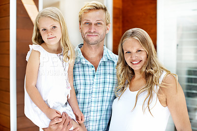 Buy stock photo Young family standing in the doorway of their home with welcoming smiles