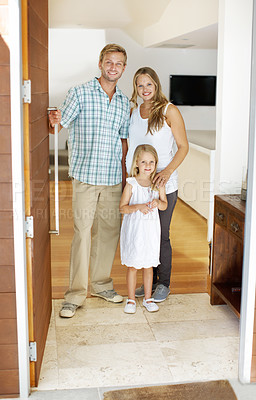 Buy stock photo Young family standing in the doorway of their home with welcoming smiles