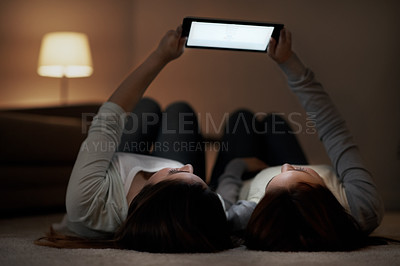 Buy stock photo Two teenage girls lying on their backs and holding a digital tablet