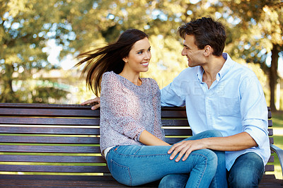 Buy stock photo Gorgeous young woman and her loving boyfriend on a shady park bench together