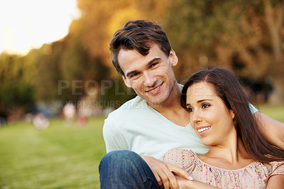 Buy stock photo Happy young couple relaxing in a park in the late afternoon - copyspace