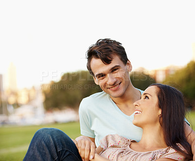 Buy stock photo Happy young couple relaxing in a park in the late afternoon - copyspace