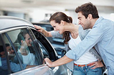 Buy stock photo Happy, car or couple at dealership with review, decision or automobile selection in showroom. Smile, choice or people with window, inspection together or vehicle evaluation in relationship purchase.