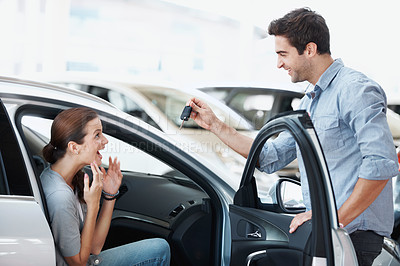 Buy stock photo Couple, keys and present for woman in car, love and surprise for partner on anniversary or milestone. Happy people, bonding and man with shocked spouse, gift and vehicle purchase at dealership