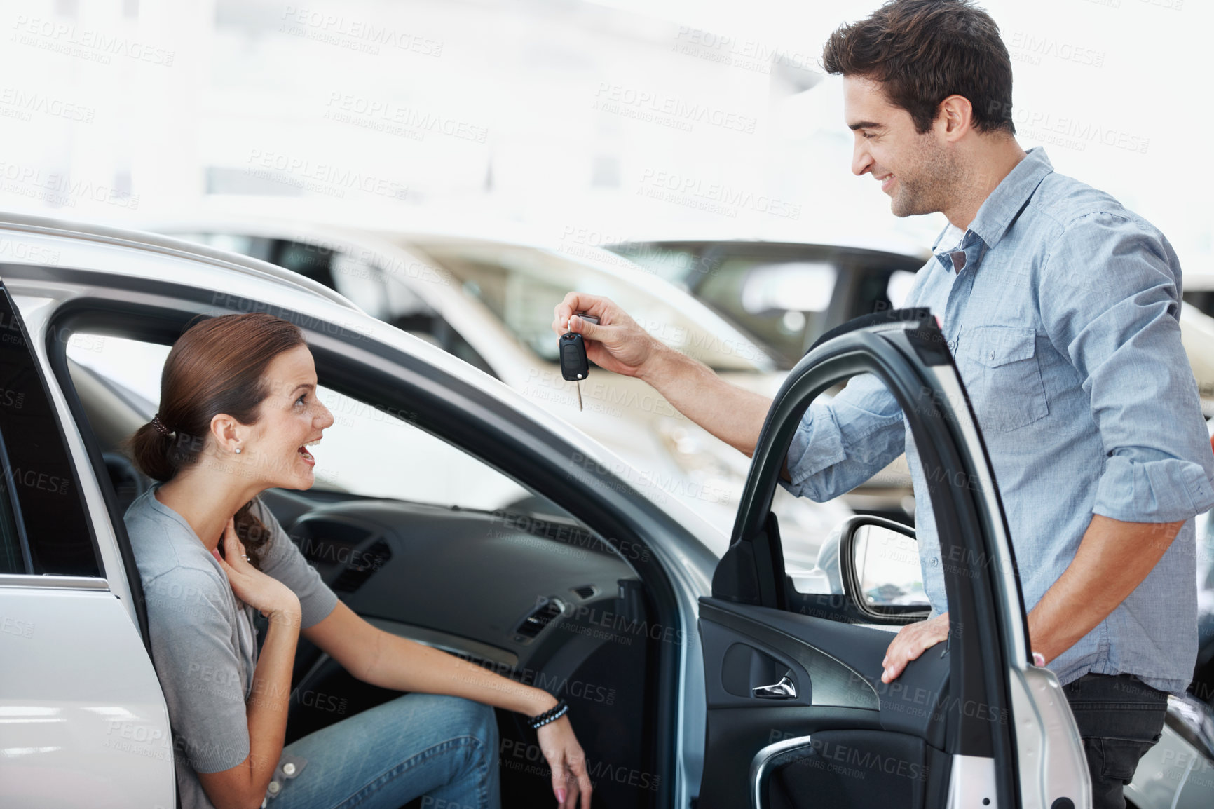 Buy stock photo Couple, surprise and keys for woman in car, love and present for partner on anniversary or milestone. Happy people, talk and man with smile for shocked spouse, gift and vehicle purchase at dealership