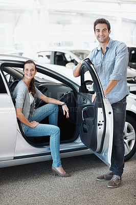 Buy stock photo Car, portrait and shopping with couple in dealership together for decision or purchase. Buying, retail and sale with happy people on showroom floor for consumerism, insurance or vehicle finance