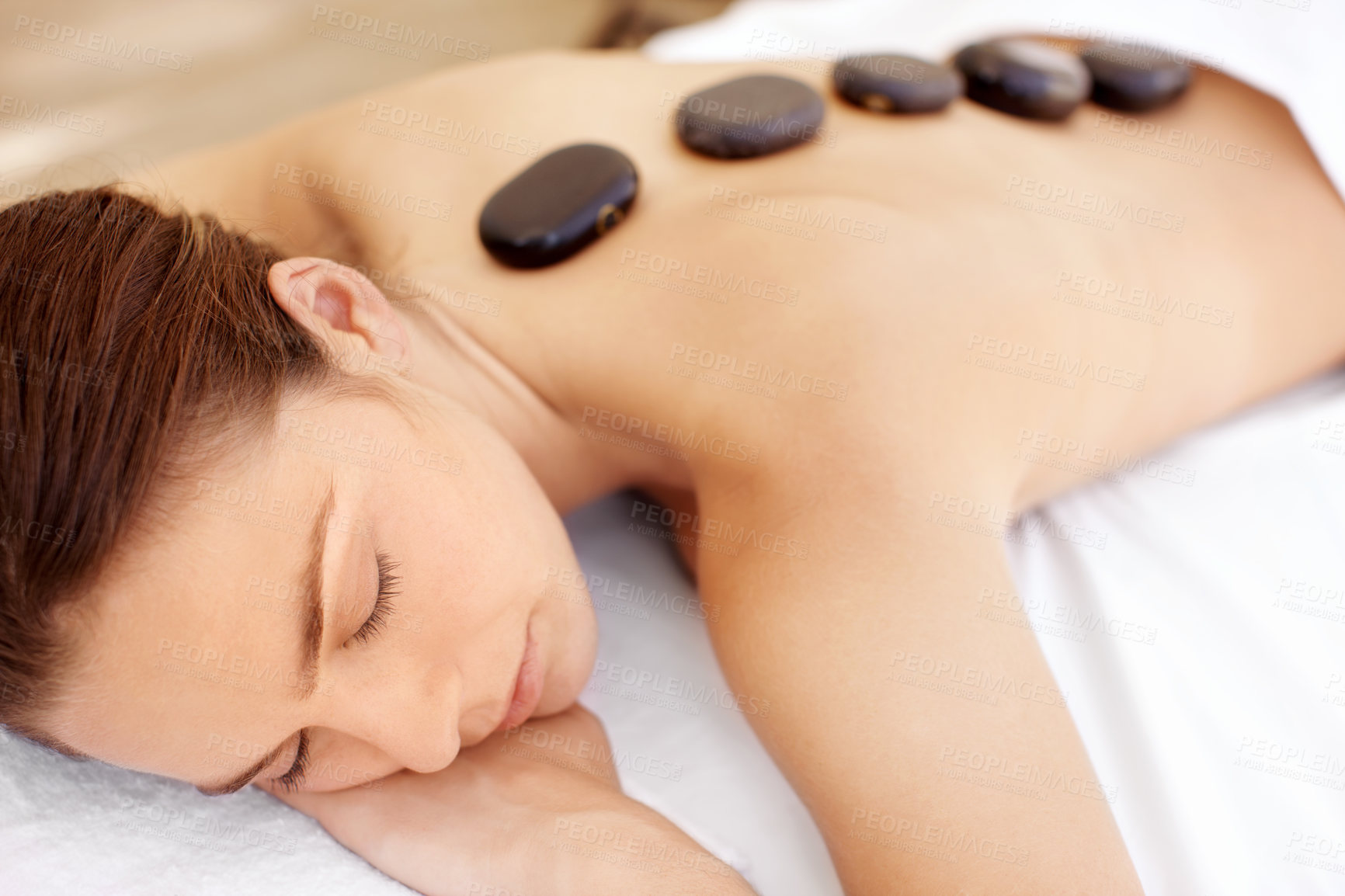 Buy stock photo Woman, spa and hot stone massage for peace, wellness and break with self care for stress relief. Female person, luxury and warm rocks on back, treatment and detox with calm and bodycare at resort
