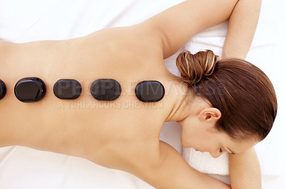 Buy stock photo Attractive young woman enjoying a hot stone treatment while lying on a spa bed 