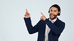 Pointing, portrait and man in studio for call center, contact us and business info on space. Mockup, happy and person with headset, gesture and advertising for customer support on white background