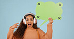 Music, woman and pointing at speech bubble with surprise, social media and mockup space. Excited, person and dialogue balloon for quote, portrait and wow with headphones on blue background in studio