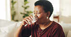 Drinking, water and black woman in sofa in home with health, wellness or digestion support. Hydration, thirst and mature person with glass of cold beverage or mineral liquid for detox in living room.