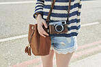 Camera, hands and tourism with woman outdoor on street in city for sightseeing or travel. Holiday, photography and vacation with tourist on sidewalk to explore destination for commute or memories