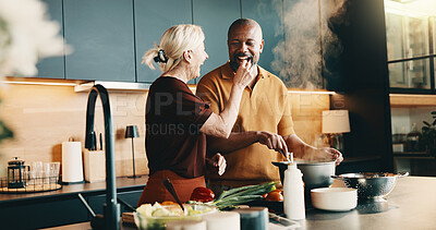 Buy stock photo Cooking, laughing and taste with interracial couple in kitchen of home together for meal preparation. Bonding, feeding and having fun with mature people in apartment for culinary hobby or eating food