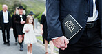 Person, hands and funeral with holy bible for memorial service, prayer or worship of god. Family, people or christianity with book, religion or faith at graveyard or cemetary for condolences or grief