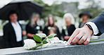 Man, hand and rose in cemetery with tombstone, funeral and people mourning for memorial service. Person, white flower and family death in graveyard outdoor with gravestone, burial ceremony and grief.