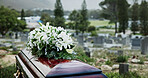 Coffin, flowers and funeral in cemetery with death, remembrance or burial ceremony for final goodbye. Casket, floral bouquet and memorial service in graveyard outdoor with honor, tribute or tradition