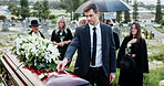 Man, funeral and rose with offering on coffin for grief or mourning death together in graveyard. Male person, sad family and empathy with flower for farewell, burial or paying respect in cemetery