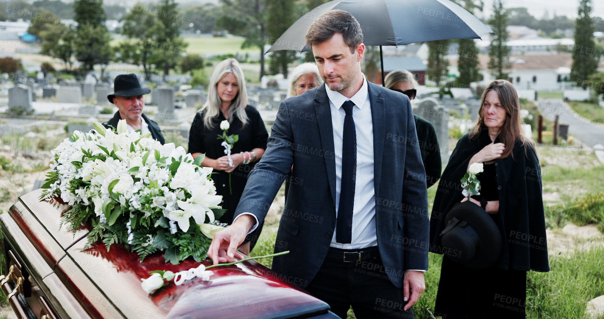 Buy stock photo Man, funeral and rose with offering on coffin for grief or mourning death together in graveyard. Male person, sad family and empathy with flower for farewell, burial or paying respect in cemetery