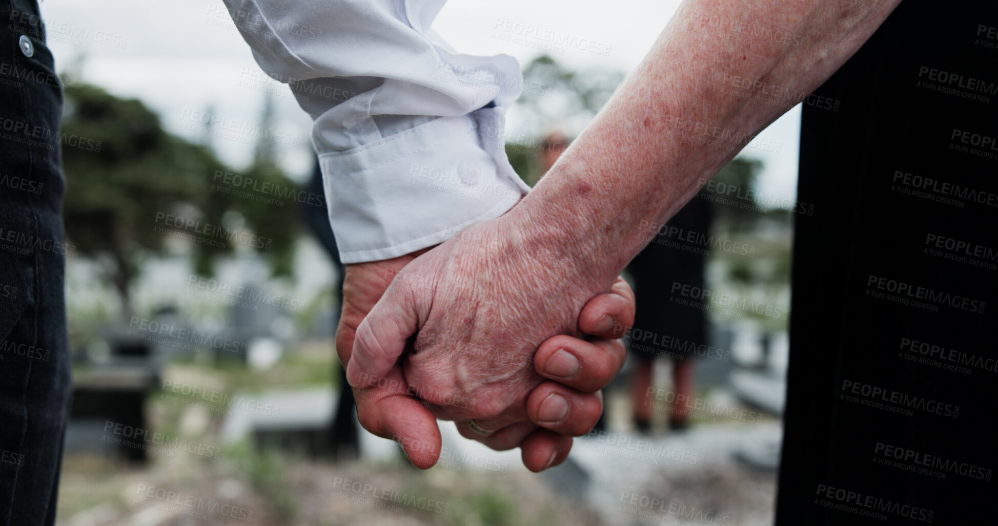 Buy stock photo Funeral, people and holding hands in cemetery with grief, mourning and empathy for burial ceremony. Family, death and senior person at graveyard outdoor with memorial service, bereavement or support.