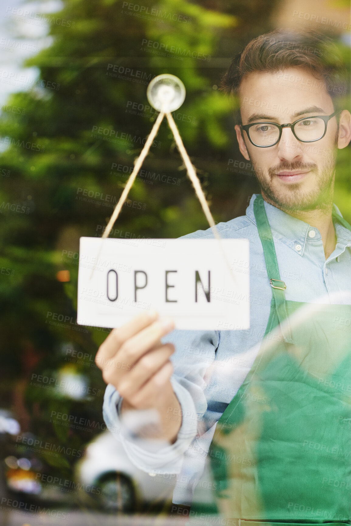 Buy stock photo Window, entrepreneur or man with open sign for restaurant, hospitality industry or ready for service. Glass, poster or business owner with welcome message for customer, smile and advertising for cafe