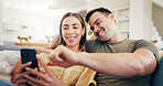 Love, phone and couple in home for relax, booking vacation or planning trip on sofa together. Technology, happy man and woman in living room, travel guide or pointing at website for holiday itinerary
