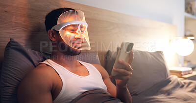 Buy stock photo Phone, bed and man with mask for skincare, research and browsing web for light therapy benefits. Smile, person and led cosmetic in home with facial tech, beauty tips and mobile app for acne treatment