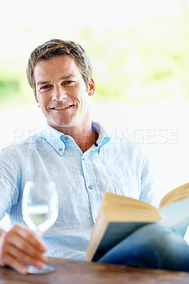 Buy stock photo Man, relax and wine glass on patio with book, peace and calm morning at holiday resort. Portrait, male person and terrace with novel, champagne and weekend break at luxury accommodation on vacation