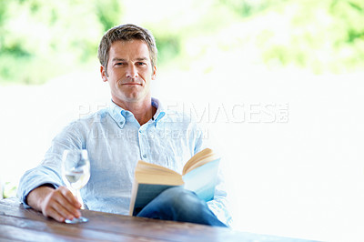 Buy stock photo Smile, man and wine glass outdoor with book, peace and calm morning at holiday resort. Portrait, person and space on patio with novel, champagne and weekend break at luxury accommodation on vacation