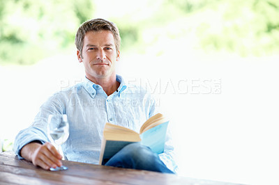 Buy stock photo Portrait, man and wine on patio with book, peace and calm morning at holiday resort. Space, male person or terrace with novel, alcohol beverage and weekend break for stress relief at vacation retreat