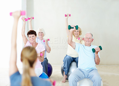 Buy stock photo Dumbbells, workout and old people in gym class with personal trainer, exercise and retirement wellness. Happy, senior group and fitness coach in health club with ball, weights and strength training.