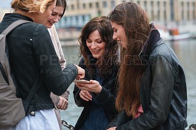 Buy stock photo Phone, smile and social media with women on promenade together for bonding, connection or typing. App, hangout and text message with girl friends outdoor at ocean for browsing, response or reunion