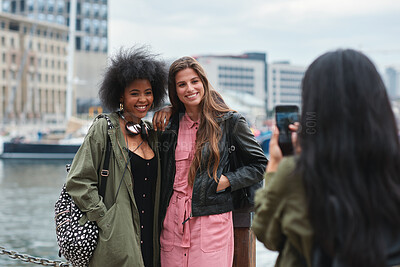 Buy stock photo Friends, photography and phone outdoor for travel, gathering or social media post on holiday. Smile, women and mobile at harbor for profile picture update, getaway reunion and memory on vacation trip